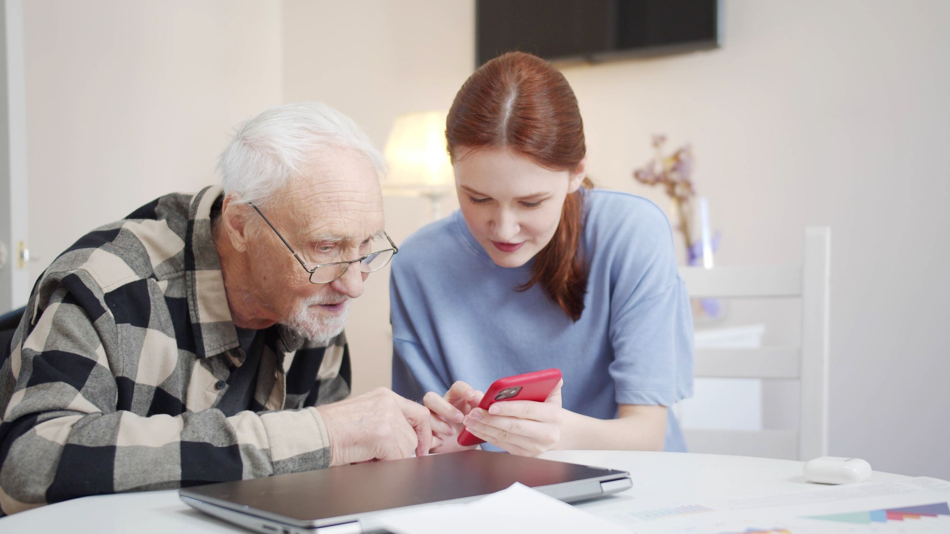 Grandpa is learning to use the phone. Social worker teaches pensioner